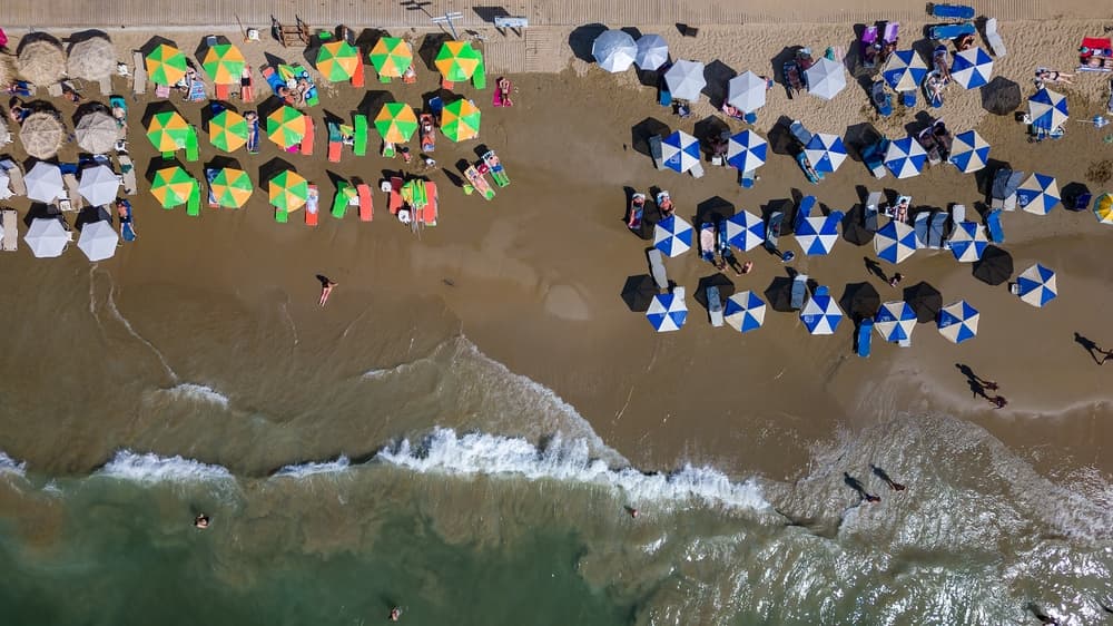 Top down aerial view of a busy beach with sun umbrellas (Nea Chora, Chania, Crete)