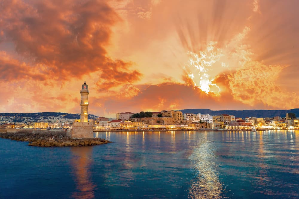 Panorama of the beautiful old harbor of Chania with the amazing lighthouse, mosque, venetian shipyards, at sunset, Crete, Greece.